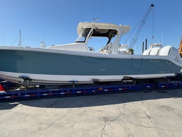 Slide: The Image of 2023 Edgewater 370 boat on trailer, blue hull, sunny day, marina background. - 3