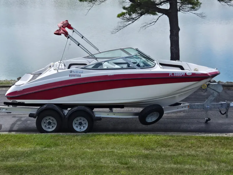 Slide: The Image of 2015 Yamaha SX190 boat on trailer by a lake, featuring red and white design. - 0