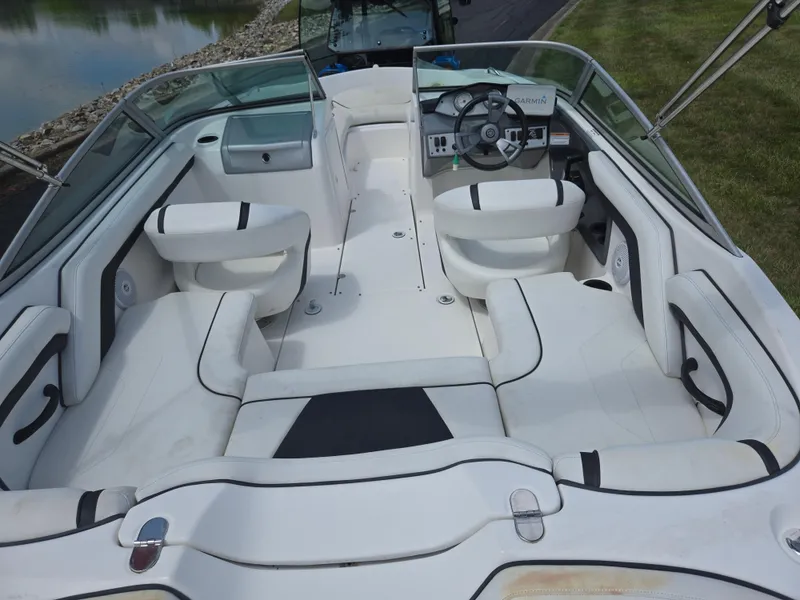 Slide: The Image of 2015 Yamaha Boats SX190 interior with white seating and steering wheel, docked near water. - 10