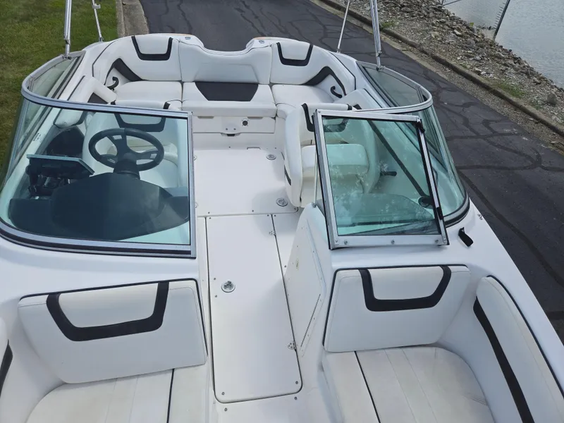Slide: The Image of 2015 Yamaha Boats SX190 interior with white seating and steering wheel, docked near water. - 20
