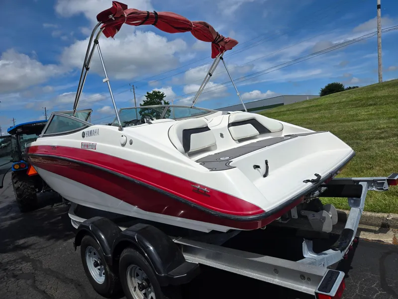 Slide: The Image of 2015 Yamaha SX190 boat on trailer, red and white design, parked outdoors under blue sky. - 3