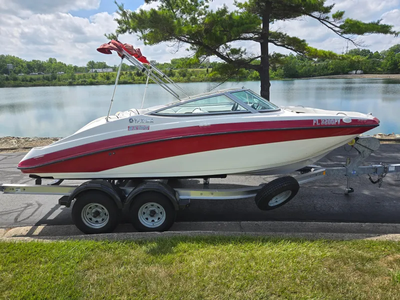 Slide: The Image of 2015 Yamaha SX190 boat on trailer by a lake, featuring red and white design. - 9