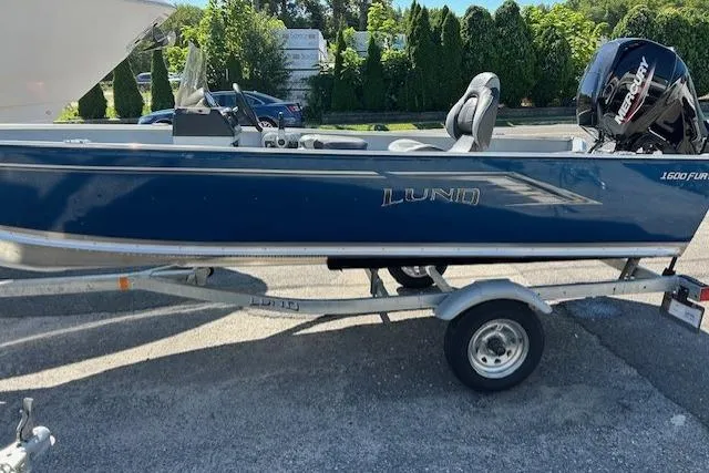 Slide: The Image of 2026 Lund 1600 Fury SS boat on trailer, blue exterior, parked outdoors. - 3