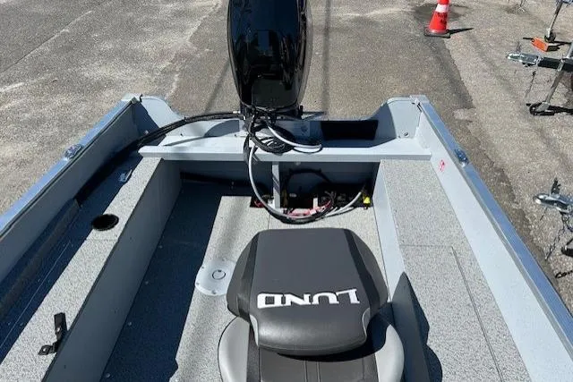 Slide: The Image of 2026 Lund 1600 Fury SS boat interior with seating and motor, parked on pavement. - 9