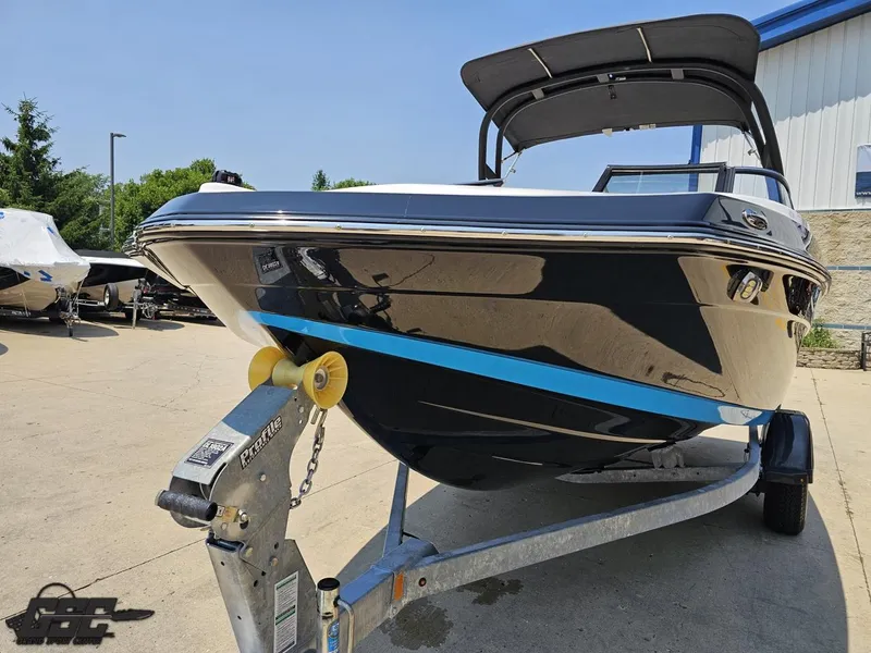 Slide: The Image of 2022 Yamaha Boats 195S on trailer, sleek black design with blue accent, parked outdoors. - 11