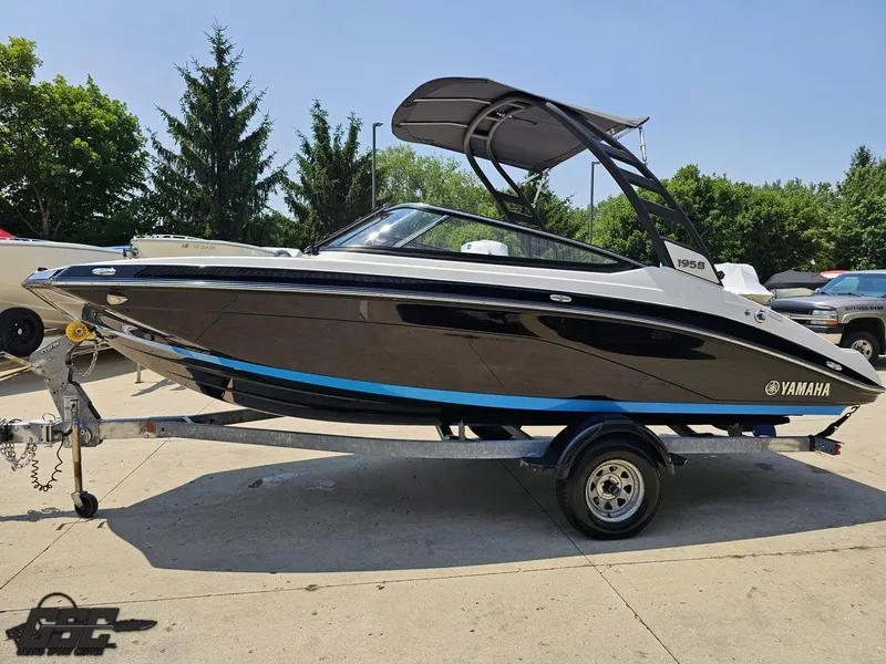 Slide: The Image of 2022 Yamaha Boats 195S on trailer, sleek black design, outdoor setting. - 16