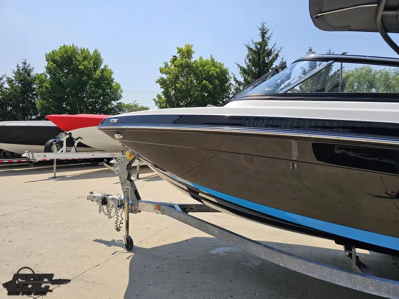 Slide: The Image of 2022 Yamaha Boats 195S on trailer, parked outdoors with trees in background. - 18