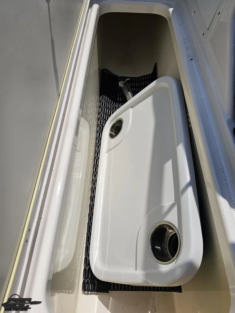 Slide: The Image of Storage compartment in a 2022 Yamaha Boats 195S, featuring a white cover with cup holders. - 45