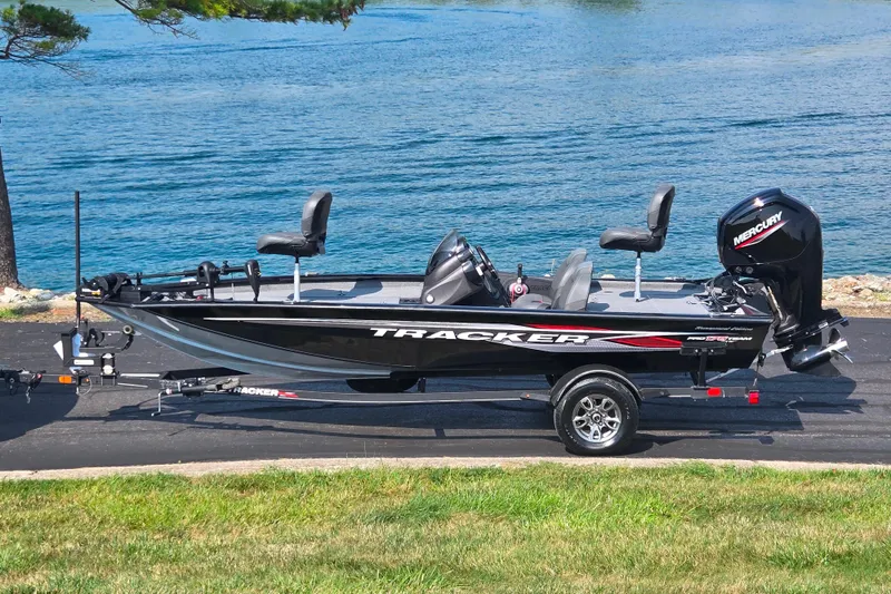 The Image of 2023 Tracker Pro Team 175 TXW fishing boat on trailer by a lake. - 0