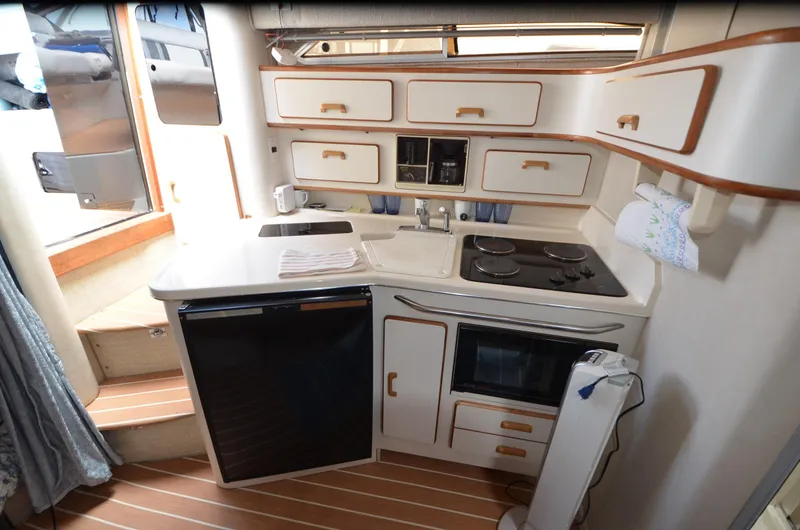 Slide: The Image of Interior of 1990 Sea Ray 350 Sundancer Coupe, featuring compact kitchen with stove and cabinets. - 13