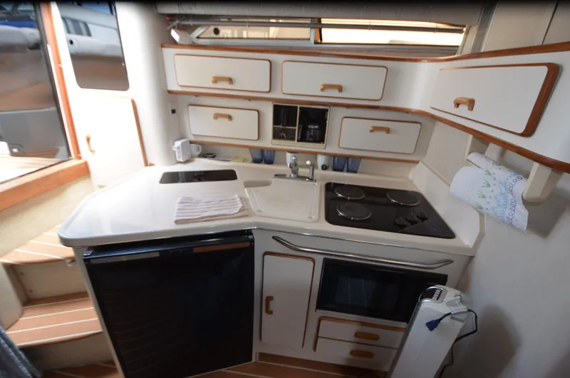 Slide: The Image of 1990 Sea Ray 350 Sundancer Coupe kitchen with stove, sink, and storage cabinets. - 19