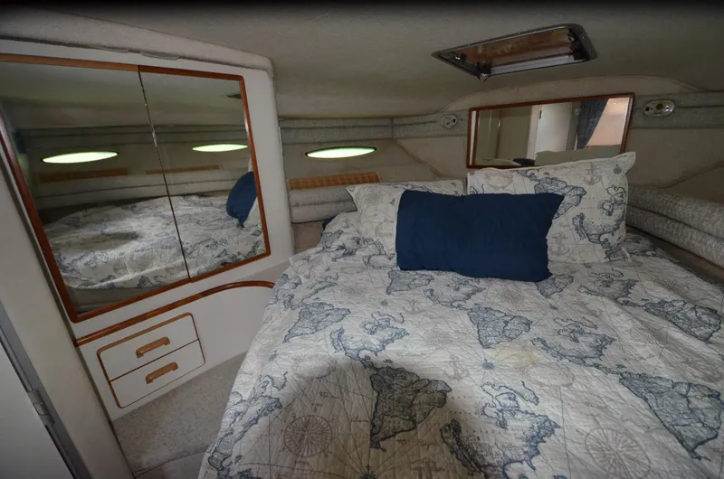 Slide: The Image of Cozy cabin interior of 1990 Sea Ray 350 Sundancer Coupe with nautical-themed bedding. - 23