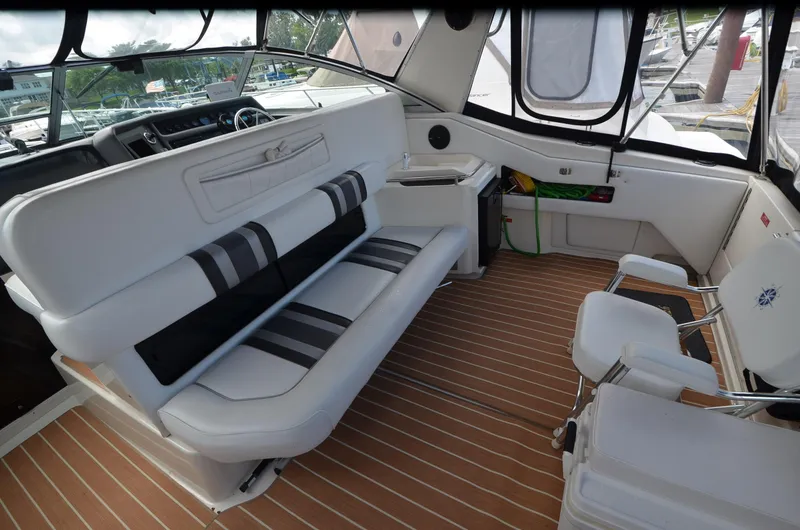 Slide: The Image of Interior of 1990 Sea Ray 350 Sundancer Coupe with white seating and wood-patterned flooring. - 7