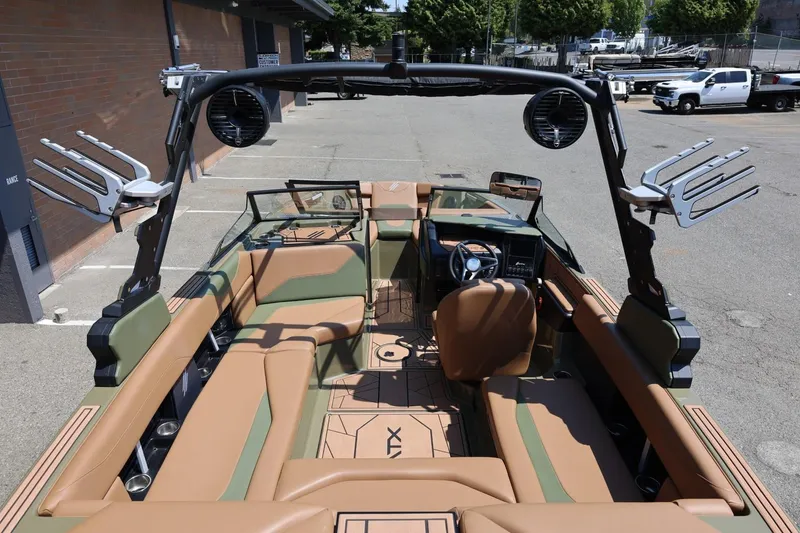 Slide: The Image of 2023 ATX Surf Boats 22 Type-S interior with tan and green seating, speakers, and wakeboard racks. - 22