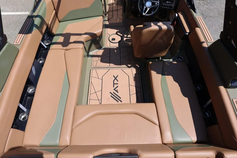 Slide: The Image of 2023 ATX Surf Boats 22 Type-S interior with tan and green seating, steering wheel, and cup holders. - 23