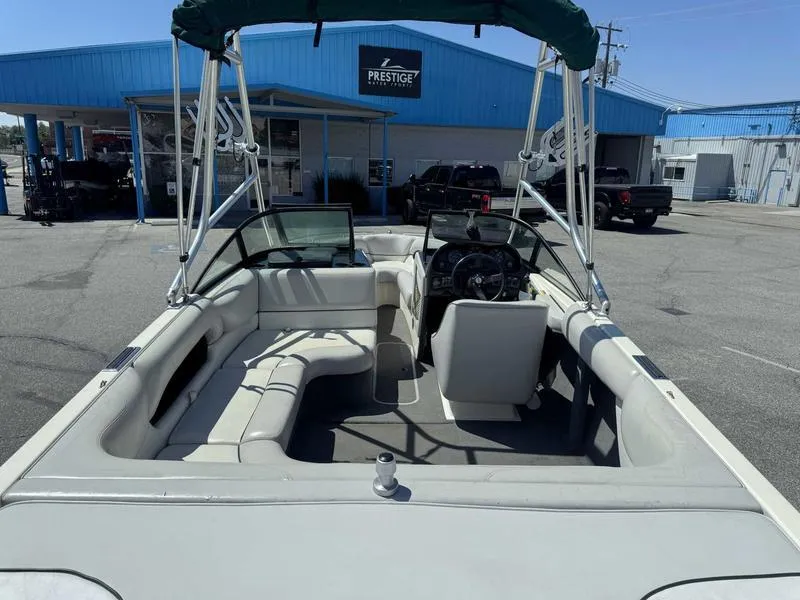 Slide: The Image of 1999 Malibu Sunsetter VLX boat with seating, parked outside a blue building. - 11