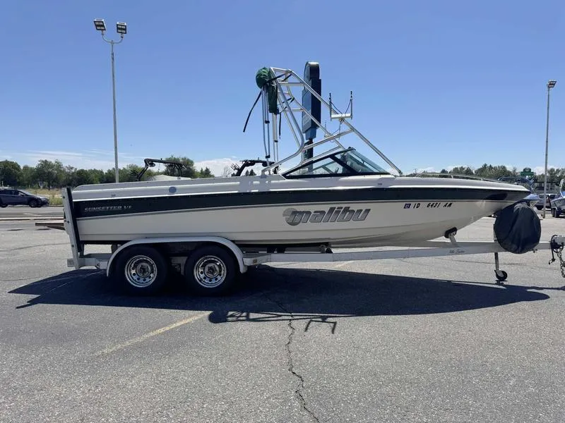 Slide: The Image of 1999 Malibu Sunsetter VLX boat on trailer in parking lot, clear sky background. - 3