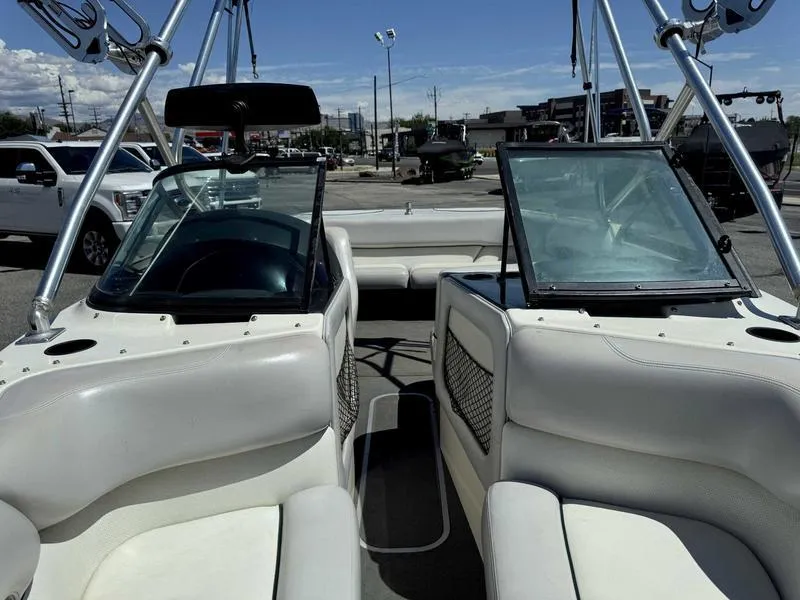 Slide: The Image of 1999 Malibu Sunsetter VLX boat interior with white seating and windshield, parked outdoors. - 8