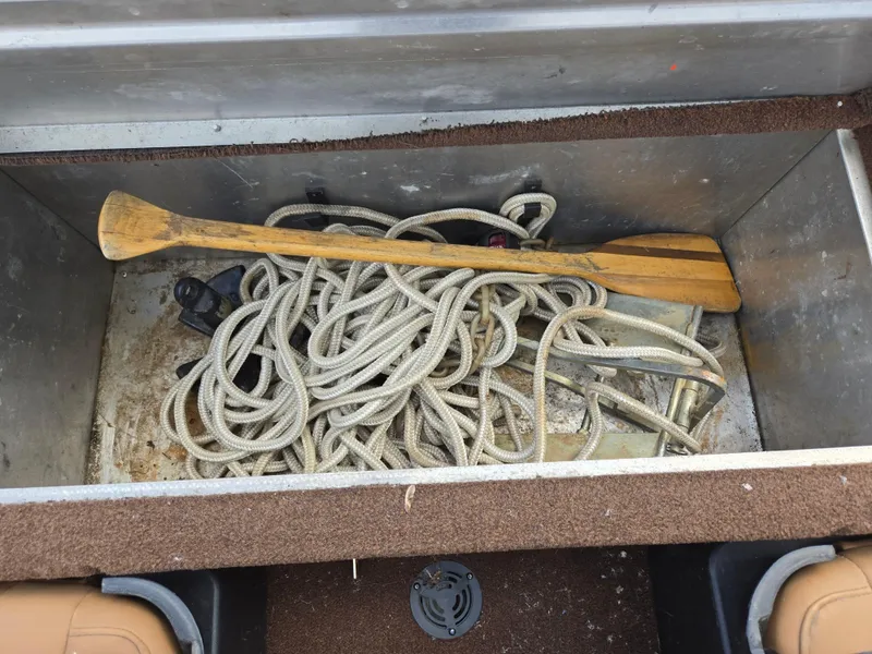 Slide: The Image of Storage compartment in 2018 Tracker Bass Tracker boat with rope and wooden paddle. - 20