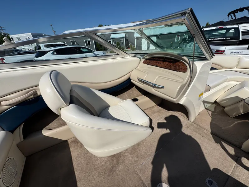 Slide: The Image of 1999 Caravelle 209 Bow Rider interior with beige seating and carpet, open windshield, and dashboard. - 11