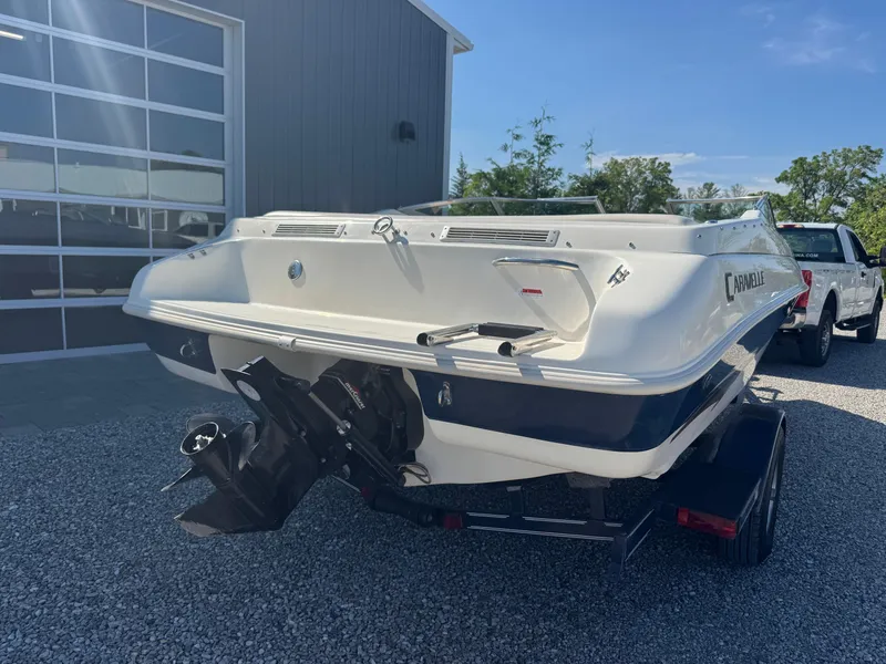 Slide: The Image of 1999 Caravelle 209 Bow Rider boat on trailer, parked outdoors near a building. - 3