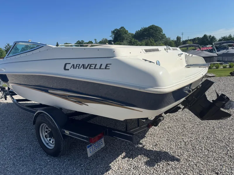 Slide: The Image of 1999 Caravelle 209 Bow Rider boat on trailer, parked on gravel, under clear blue sky. - 7