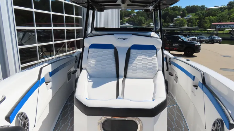 Slide: The Image of 2023 Sunsation 32 CCX boat interior with white and blue seating, docked outdoors. - 18