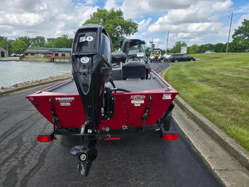 Slide: The Image of 2024 Tracker Bass Tracker Classic XL boat with 50 HP engine, parked near a lake. - 2