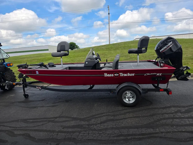 Slide: The Image of 2024 Tracker Bass Tracker Classic XL boat with Mercury engine on trailer, parked outdoors. - 4