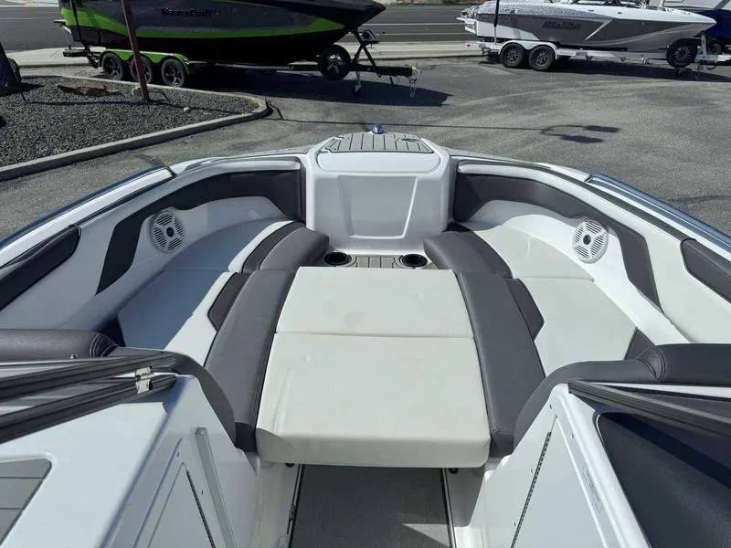 Slide: The Image of 2022 Yamaha Boats SX210 interior with cushioned seating and cup holders, parked on a trailer. - 16