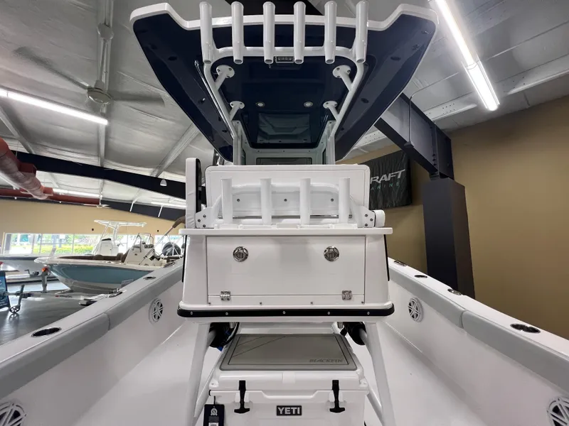 Slide: The Image of 2026 Blackfin 242 HB boat interior with rod holders and Yeti cooler in showroom. - 12