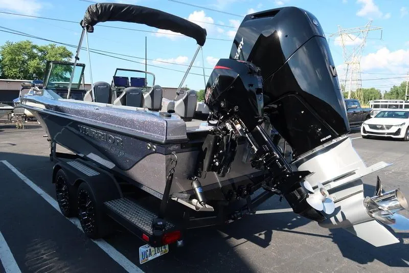 Slide: The Image of 2024 Warrior 238 DC boat with powerful outboard motor, parked on a trailer. - 10