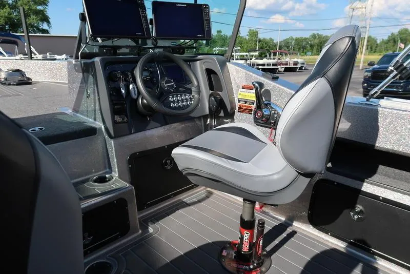 Slide: The Image of 2024 Warrior 238 DC boat cockpit with steering wheel, dual screens, and comfortable seating. - 13