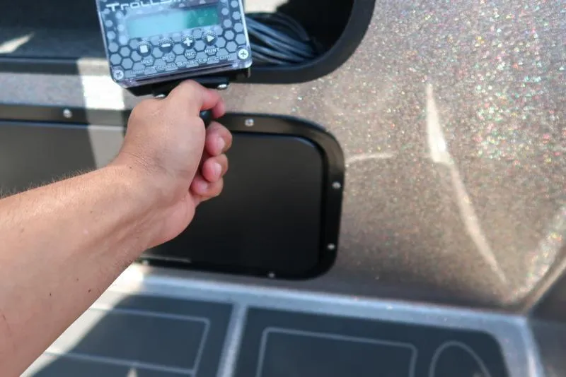 Slide: The Image of Hand holding a control device on a 2024 Warrior 238 DC boat dashboard. - 15