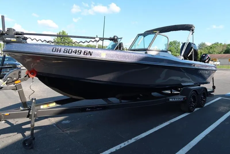 Slide: The Image of 2024 Warrior 238 DC boat on trailer, parked outdoors under clear sky. - 9