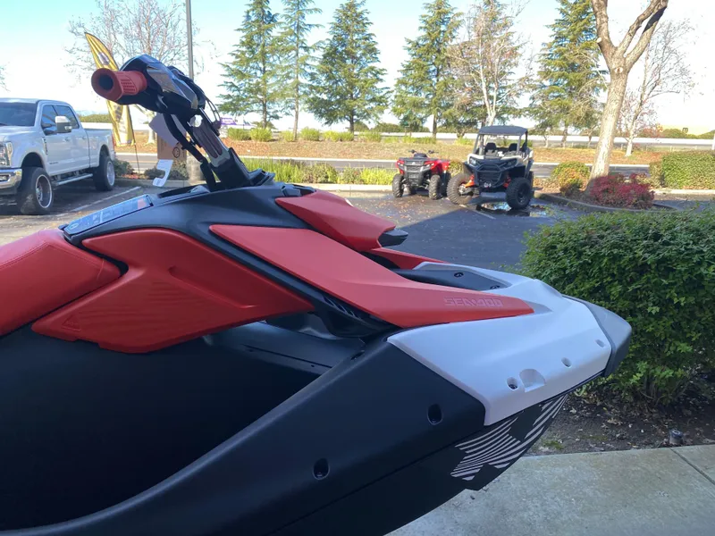 Slide: The Image of 2024 Sea-Doo Spark Trixx jet ski, red and black, parked outdoors. - 11