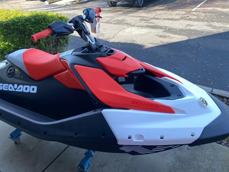 Slide: The Image of 2024 Sea-Doo Spark Trixx jet ski with red and black design, parked outdoors. - 12