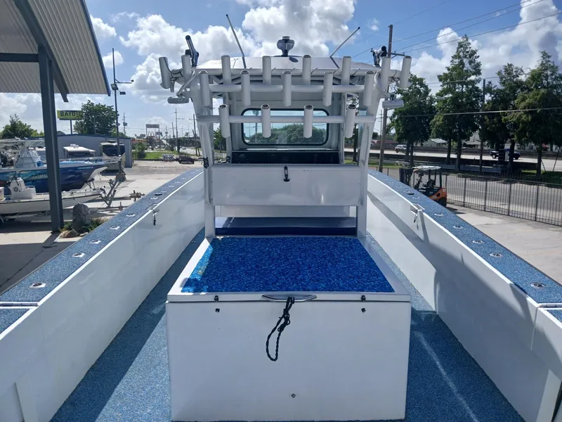 Slide: The Image of 2023 Razor Cat 37 Cat boat with blue deck, rod holders, and cabin, parked outdoors. - 12