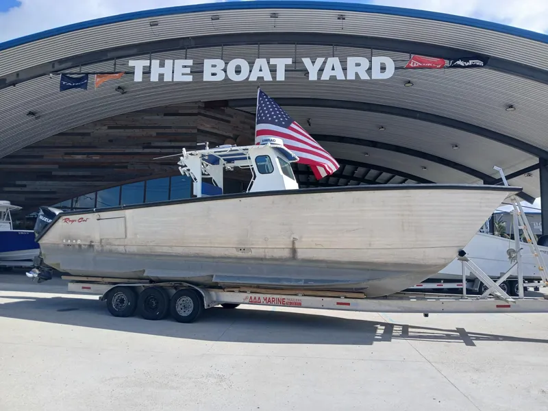 Slide: The Image of 2023 Razor Cat 37 Cat boat on trailer at The Boat Yard, American flag displayed. - 29