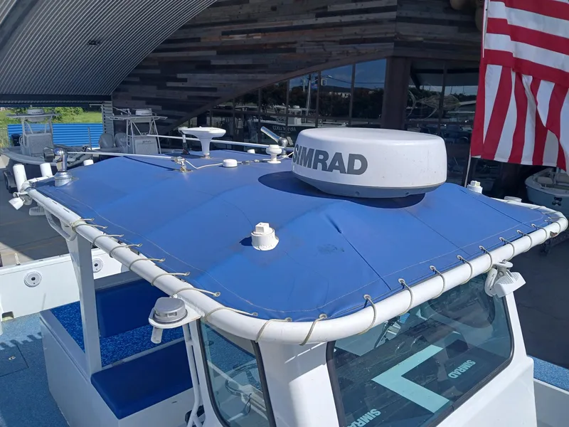 Slide: The Image of 2023 Razor Cat 37 Cat boat with blue canopy and Simrad radar, docked near American flag. - 3