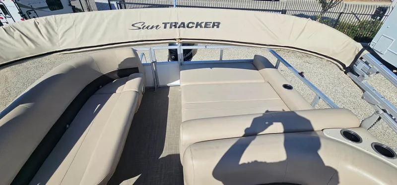 Slide: The Image of 2017 Sun Tracker Party Barge 240 with beige seating and canopy, docked outdoors. - 9