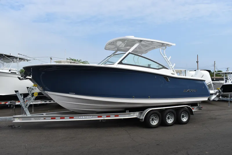 The Image of 2025 Blackfin 272 DC boat on trailer, blue hull, parked outdoors. - 1