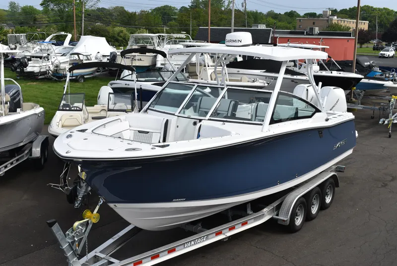 Slide: The Image of 2025 Blackfin 272 DC boat on trailer, displayed in a marina with other boats. - 2
