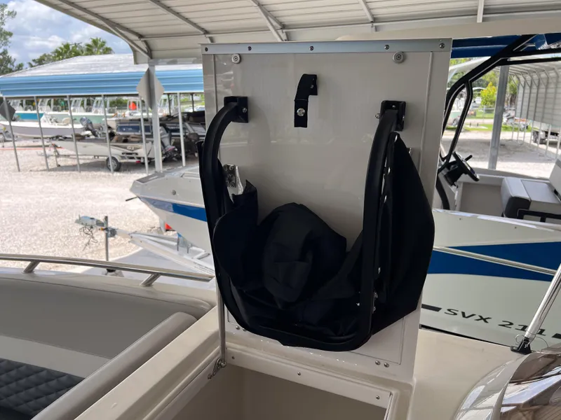Slide: The Image of 2026 Starcraft SVX 231 OB boat storage compartment with black bag under covered dock. - 22