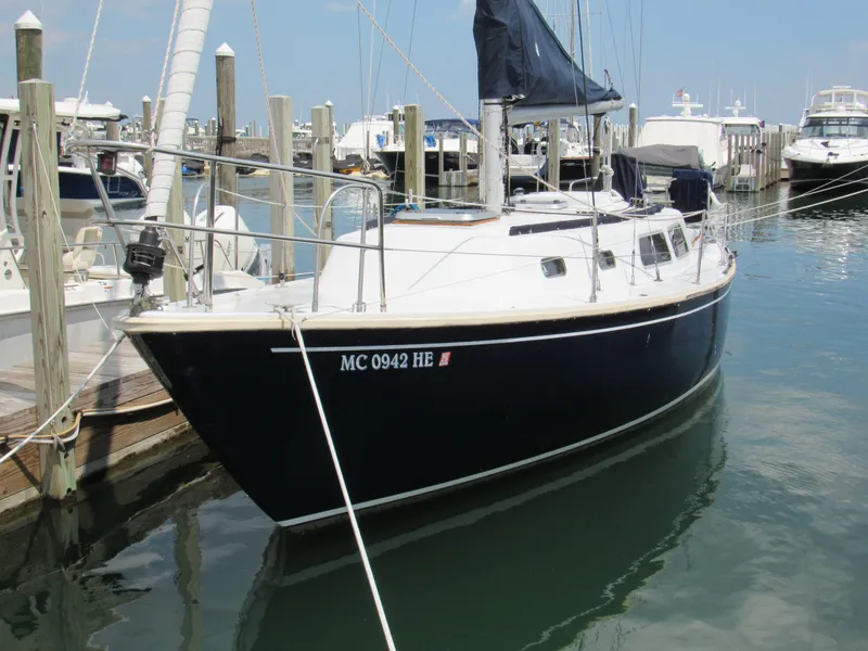 The Image of 1968 CAL 34 sailboat docked in marina, featuring sleek black hull and white deck. - 1