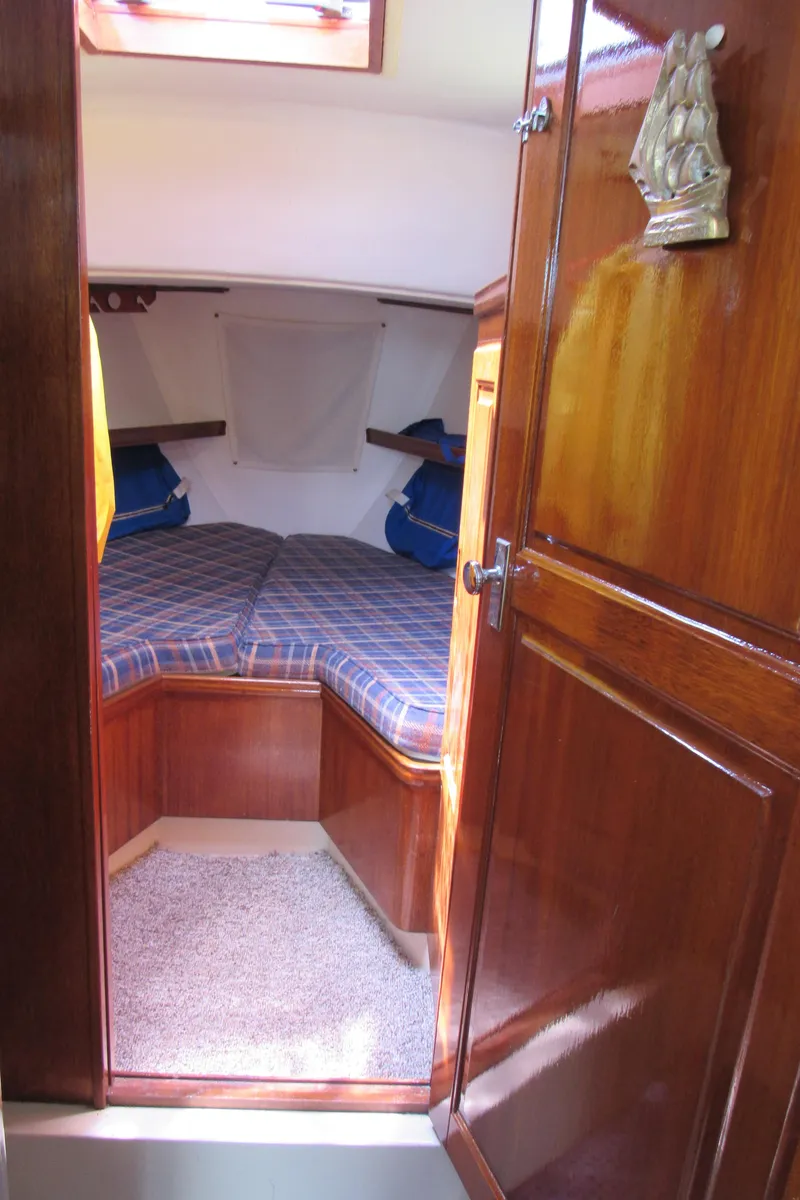 Slide: The Image of Cozy cabin interior of a 1968 CAL 34 sailboat with wooden finishes and plaid bedding. - 11