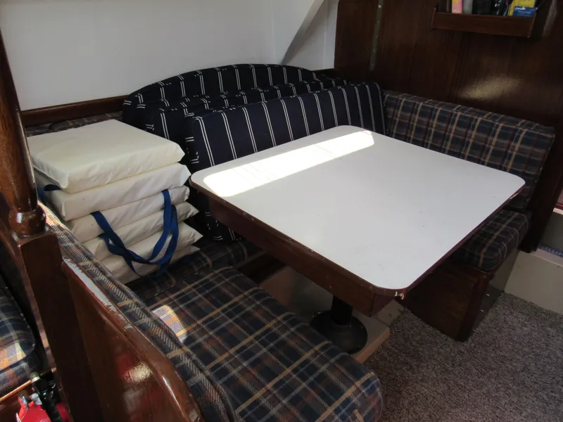 Slide: The Image of Cozy dining area in a 1968 CAL 34 sailboat with plaid seating and white table. - 3