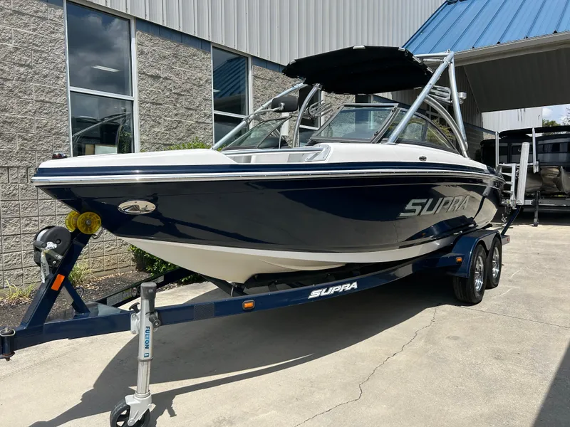 Slide: The Image of 2010 Supra Launch 21 V boat on trailer, parked outside a building. - 2