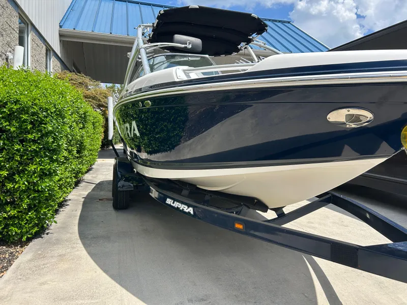 Slide: The Image of 2010 Supra Launch 21 V boat on trailer, parked outdoors under blue sky. - 3