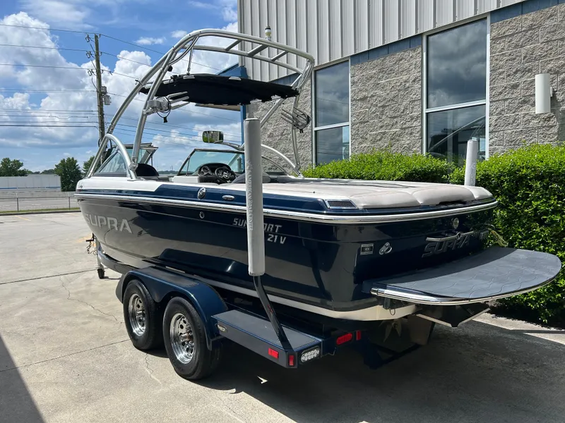 Slide: The Image of 2010 Supra Launch 21 V boat on trailer, parked outdoors near a building. - 6